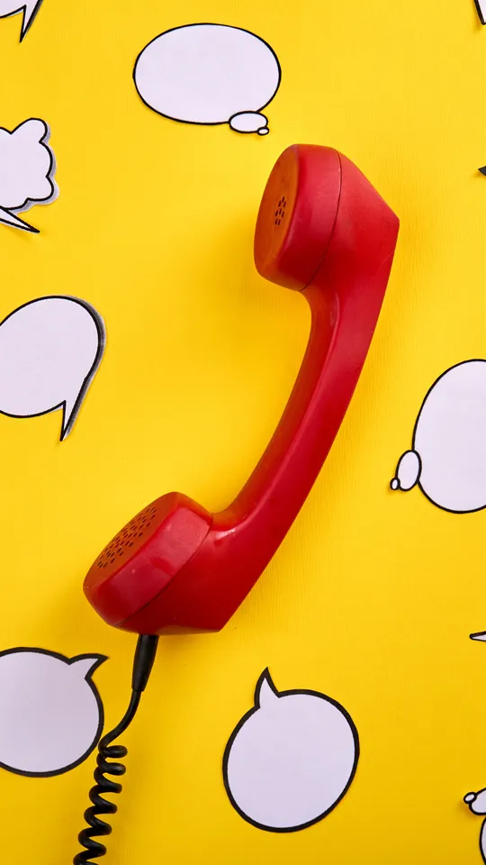 Cornetta del telefono rossa su sfondo giallo
